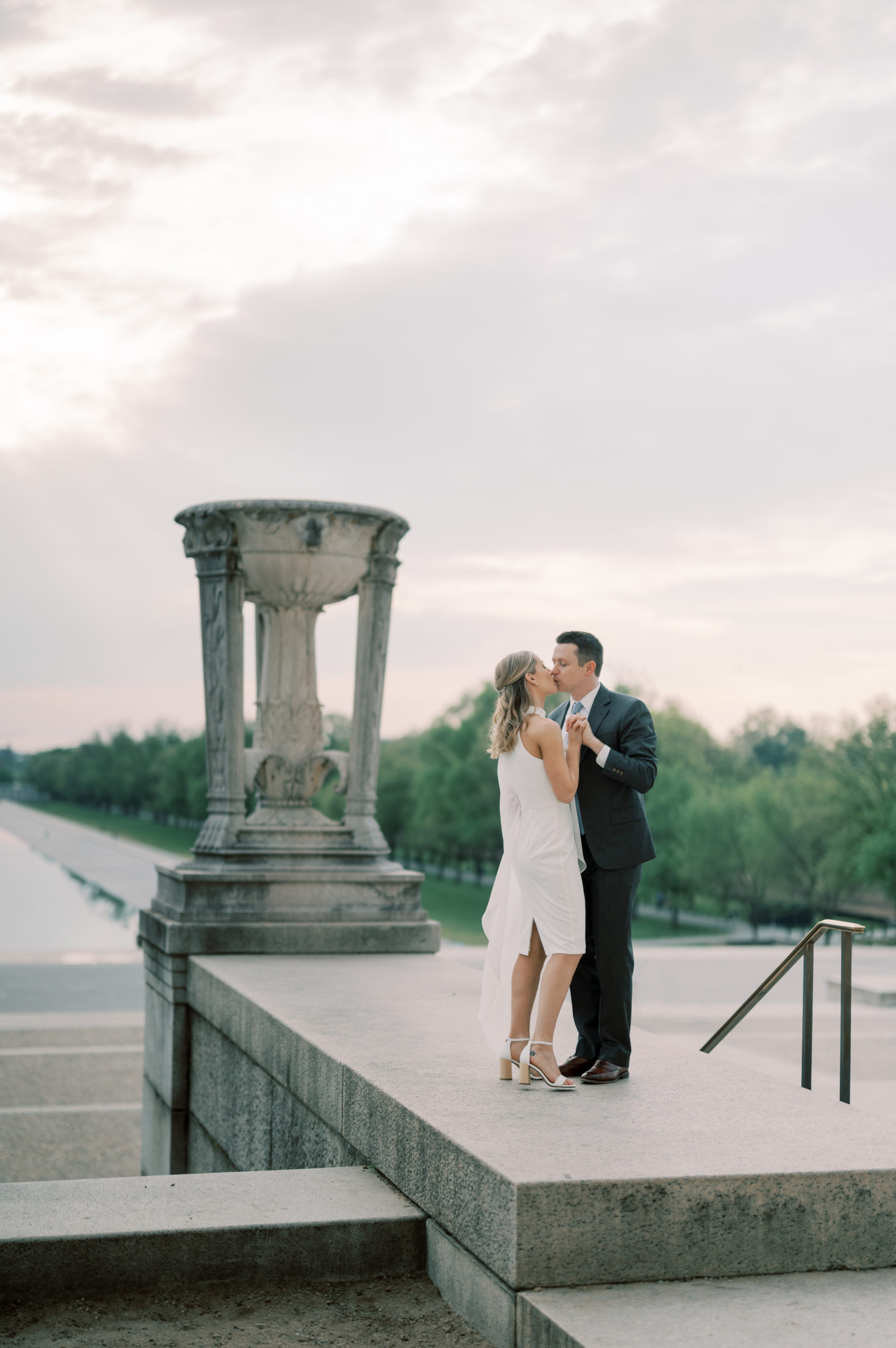 engagement photo of couple kissing at the lincoln memorial in washington dc overlooking the reflecting pool and washington monument