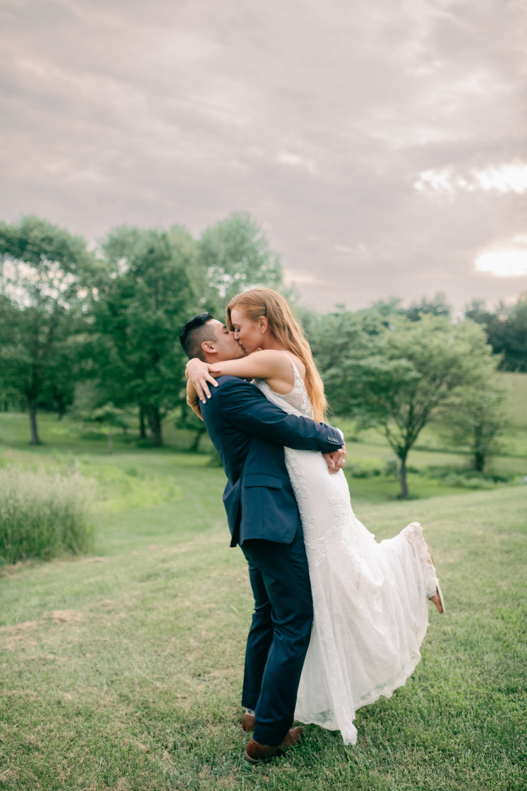 groom lifting up his bride and kissing her at glen ellen farm by dc wedding photographer omar and company